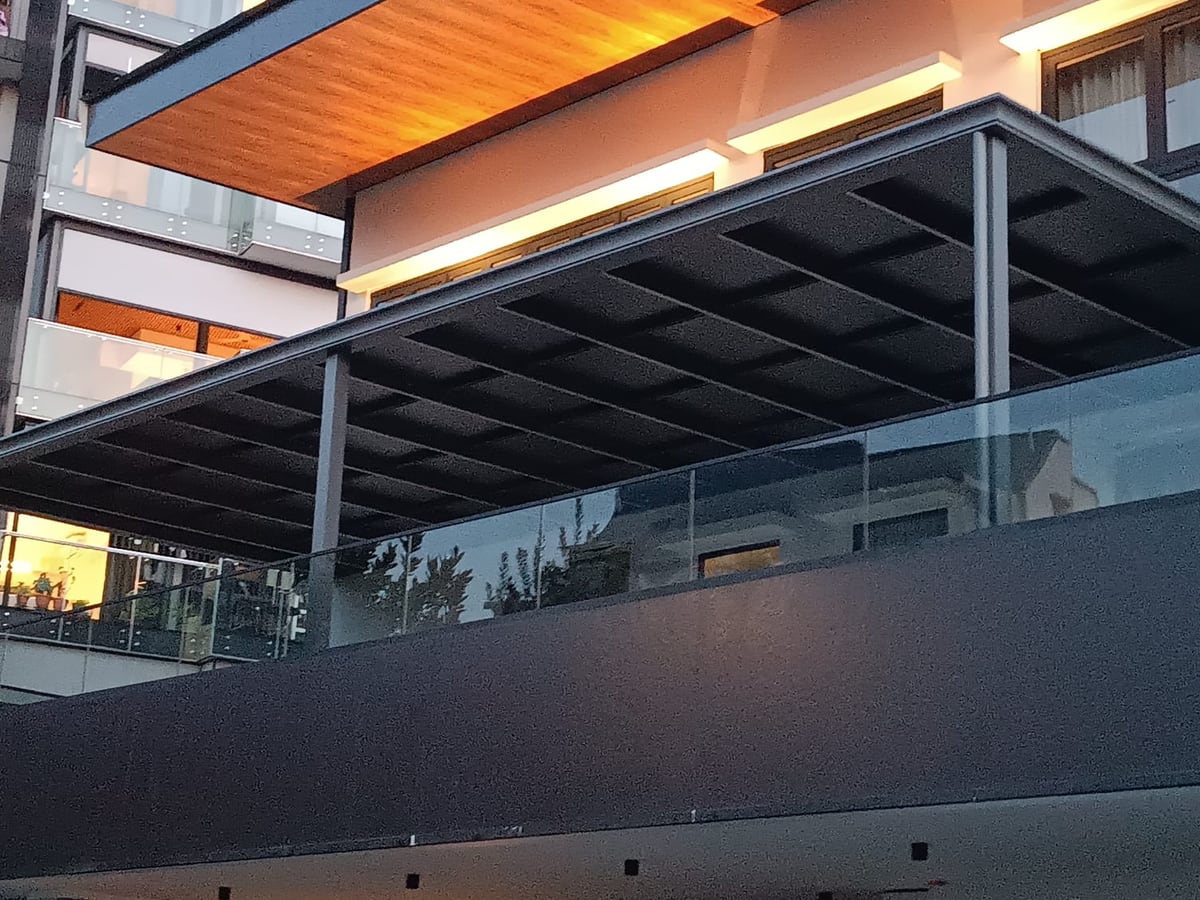 Aluminium shelter with warm timber look soffit above a balcony